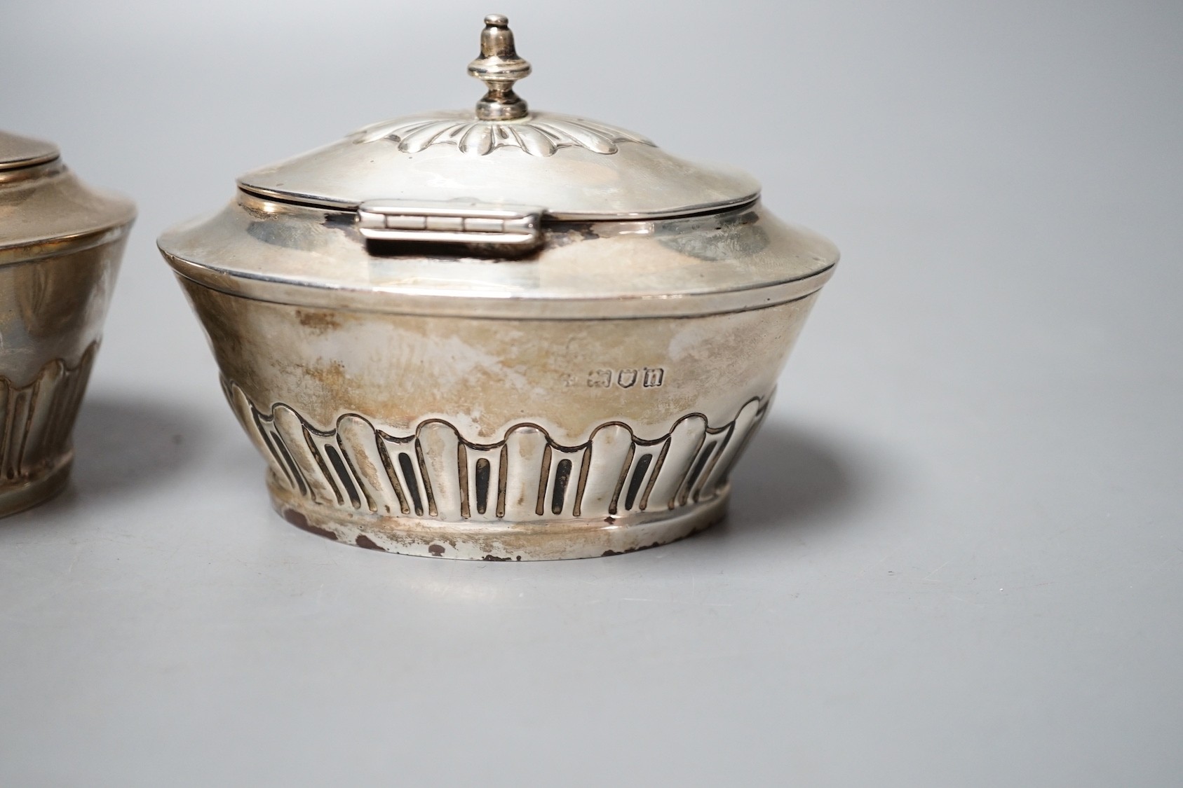 A matched pair of early 20th century silver oval tea caddies, London, 1908 & 191, width 10.5cm and two early 20th century silver leaf caddy spoons, one Britannia standard.